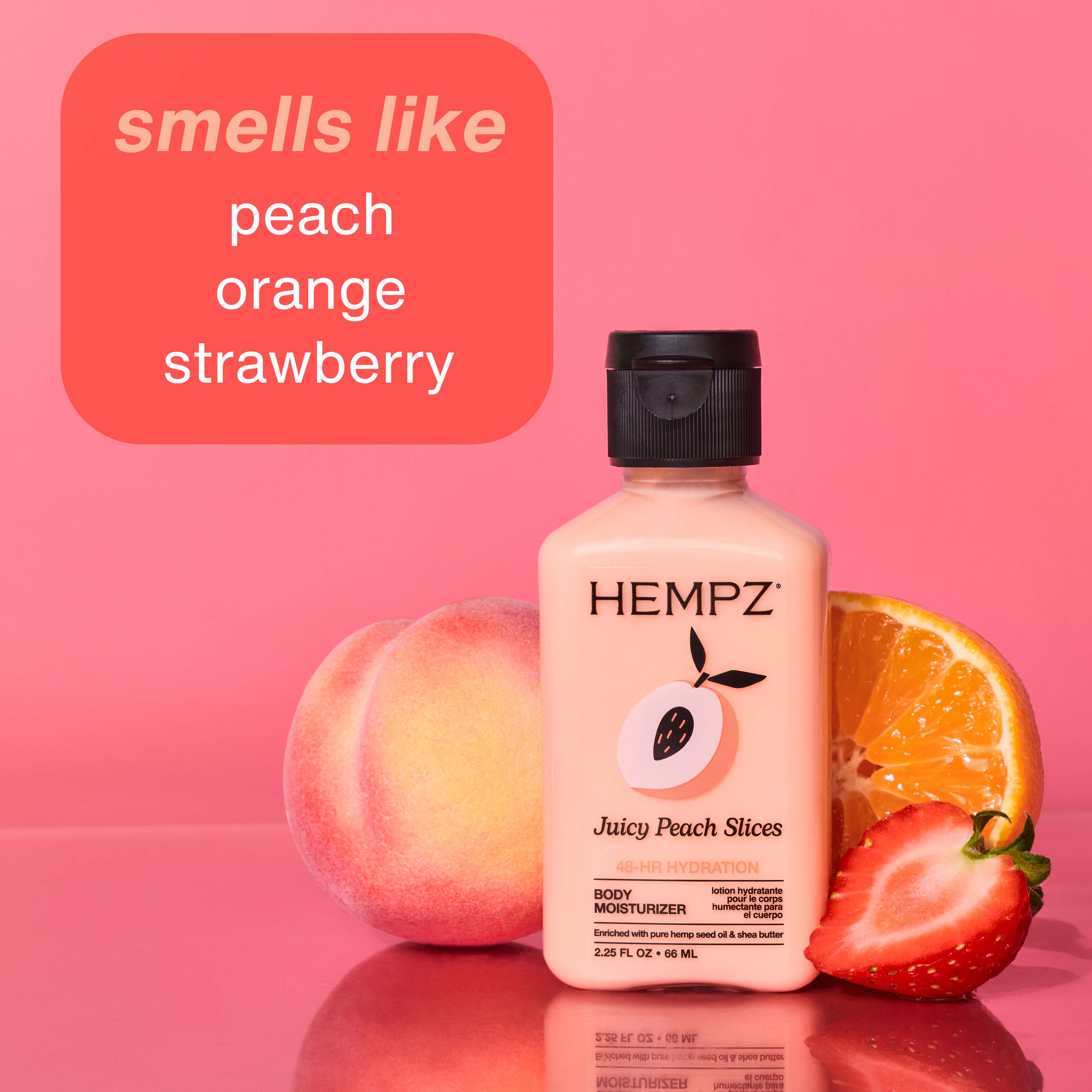 Hempz mini body moisturizer bottle with peach, orange, and strawberry on a pink background